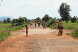 In sella alla mia bici accosto lungo la strada, fiancheggiata da risaie a perdita d’occhio. Le allungo una maglietta e a gesti le faccio capire che è per lei. Photo by Elisa